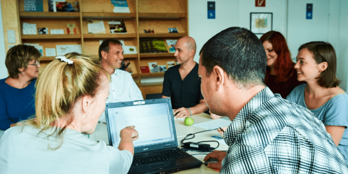 Menschen sitzen rund um einen Tisch im Büro der Genossenschaft für Gemeinwohl